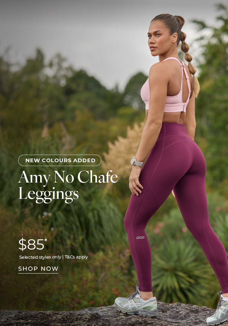 Woman standing on a rock in a natural outdoor setting, wearing a pink Lorna Jane sports bra and burgundy Amy No Chafe Leggings. Text: New Colours Added. Amy No Chafe Leggings $85* Selected styles only | T&Cs apply - Shop Now
