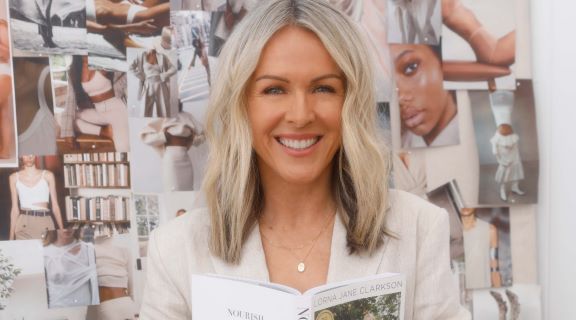 Photo of Lorna Jane Clarkson standing infront of a wall with magazine clippings