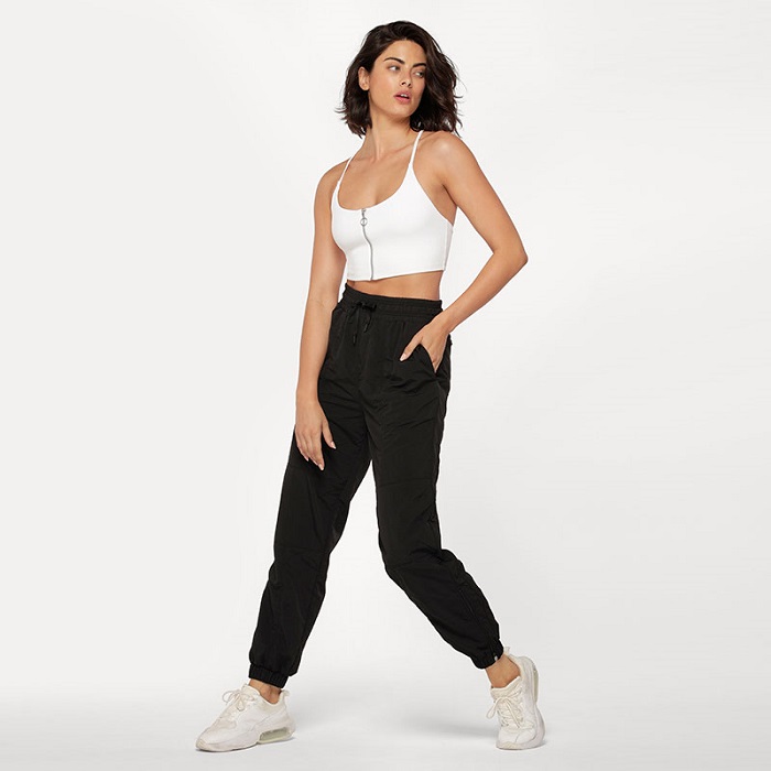 woman wearing black off duty tracksuit pants and white zip front closure sports bra