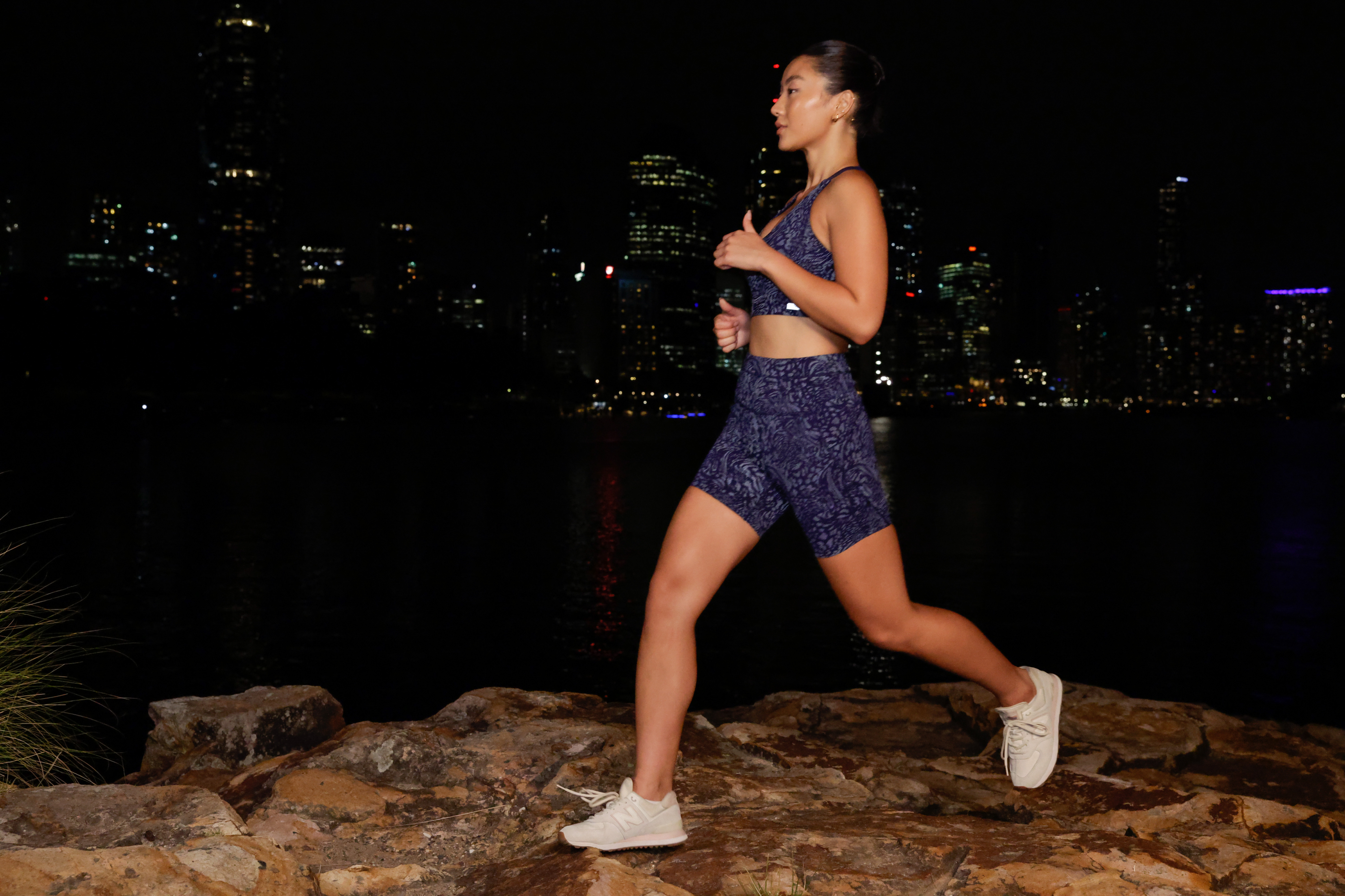 Woman running at night wearing reflective print sports bra and bike shorts