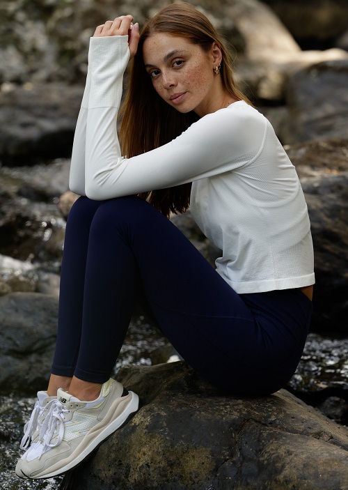 woman wearing a white long sleeve top and full length navy blue thermal leggings