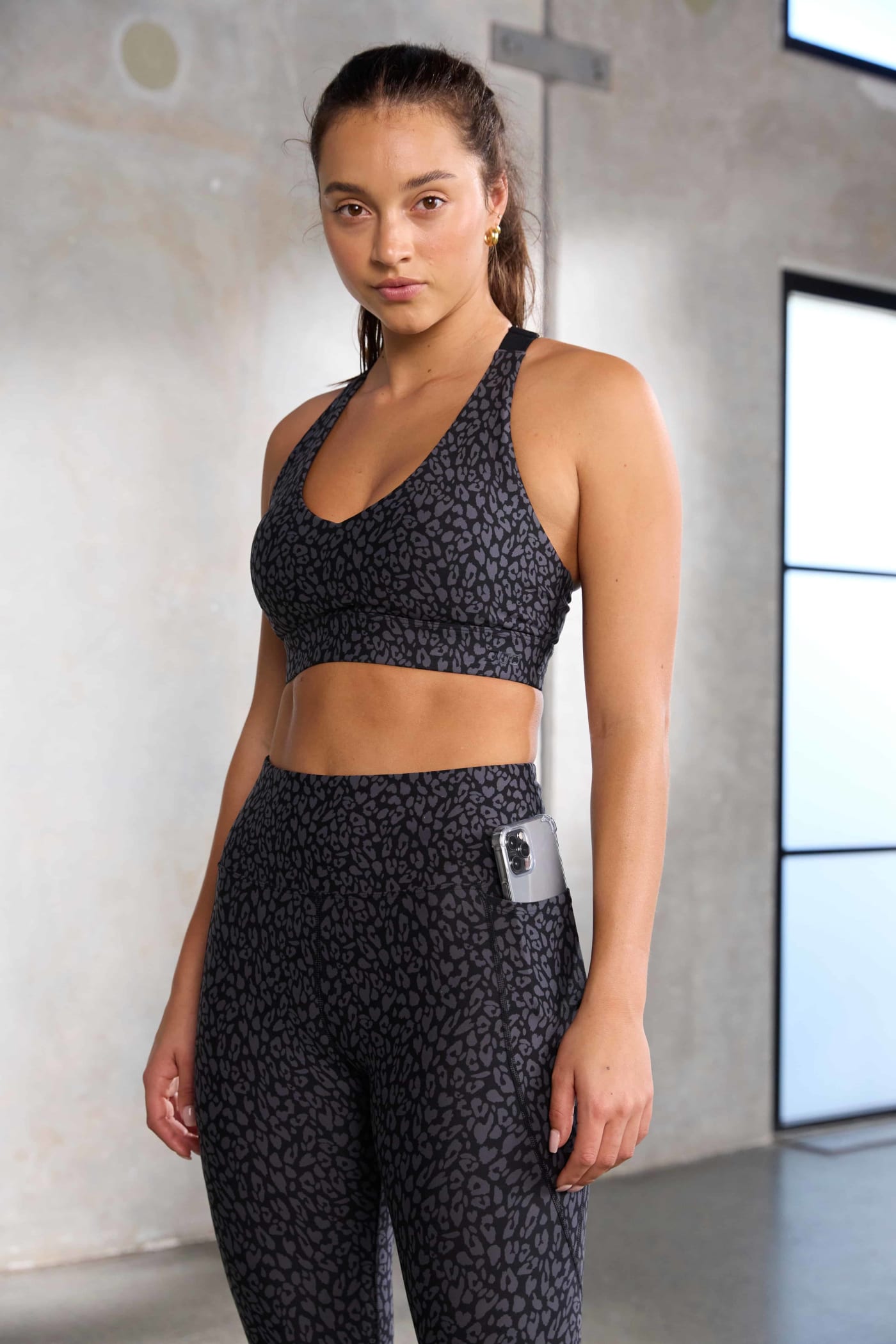 Front shot of a model wearing an animal print sports bra and leggings with a phone pocket on the side of the leg.