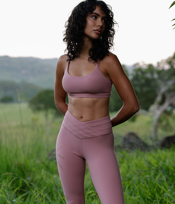 a woman wearing pink leggings and a strappy sports bra