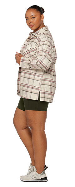 a woman wearing khaki green bike shorts and a white and pink check flannel shirt