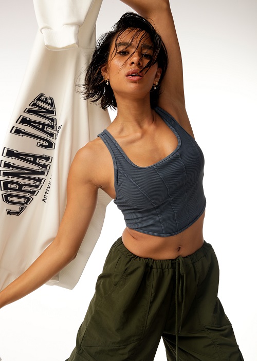 woman wearing denim coloured sports bra while green cargo pants holding a white jumper