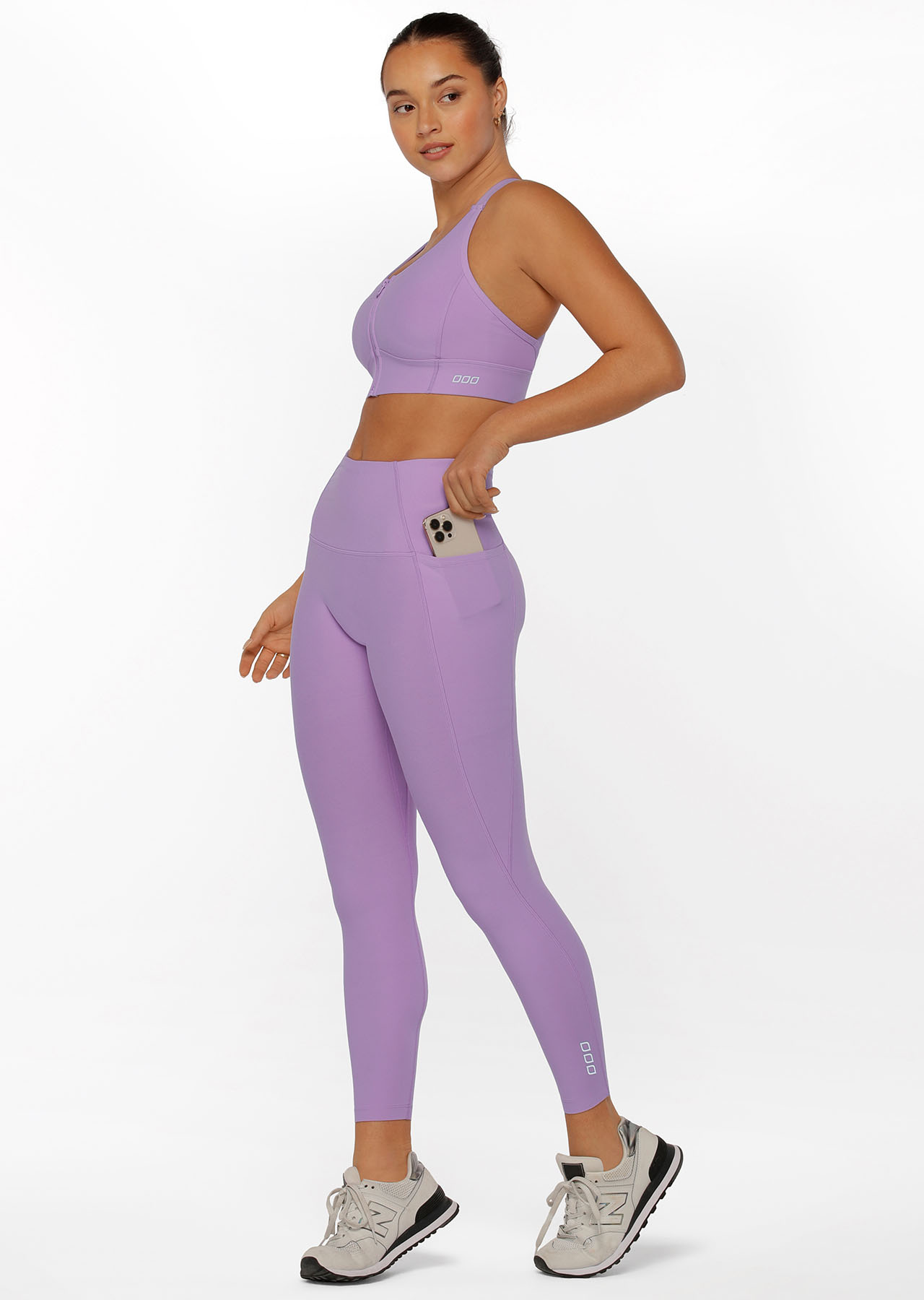 Model wearing lilac coloured sports bra and leggings with phone pockets